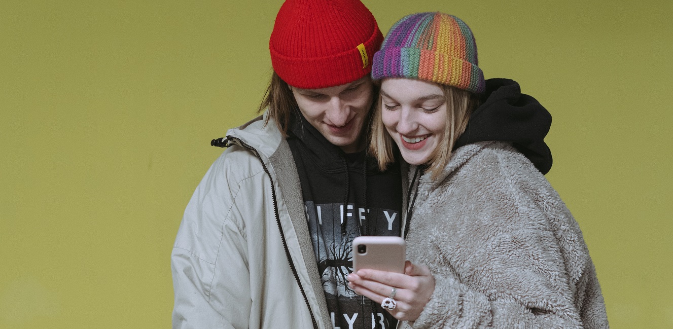 Zwei Teenager schauen lächelnd auf ein Smartphone.