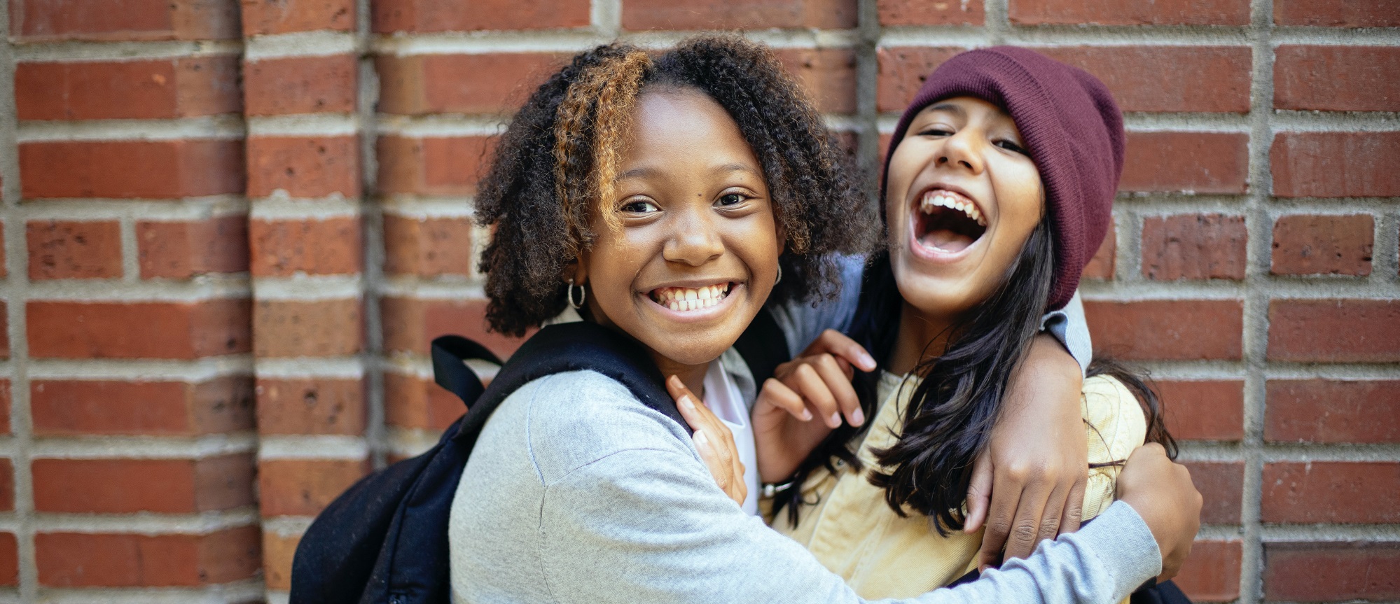 Zwei junge Mädchen lachen und umarmen sich.