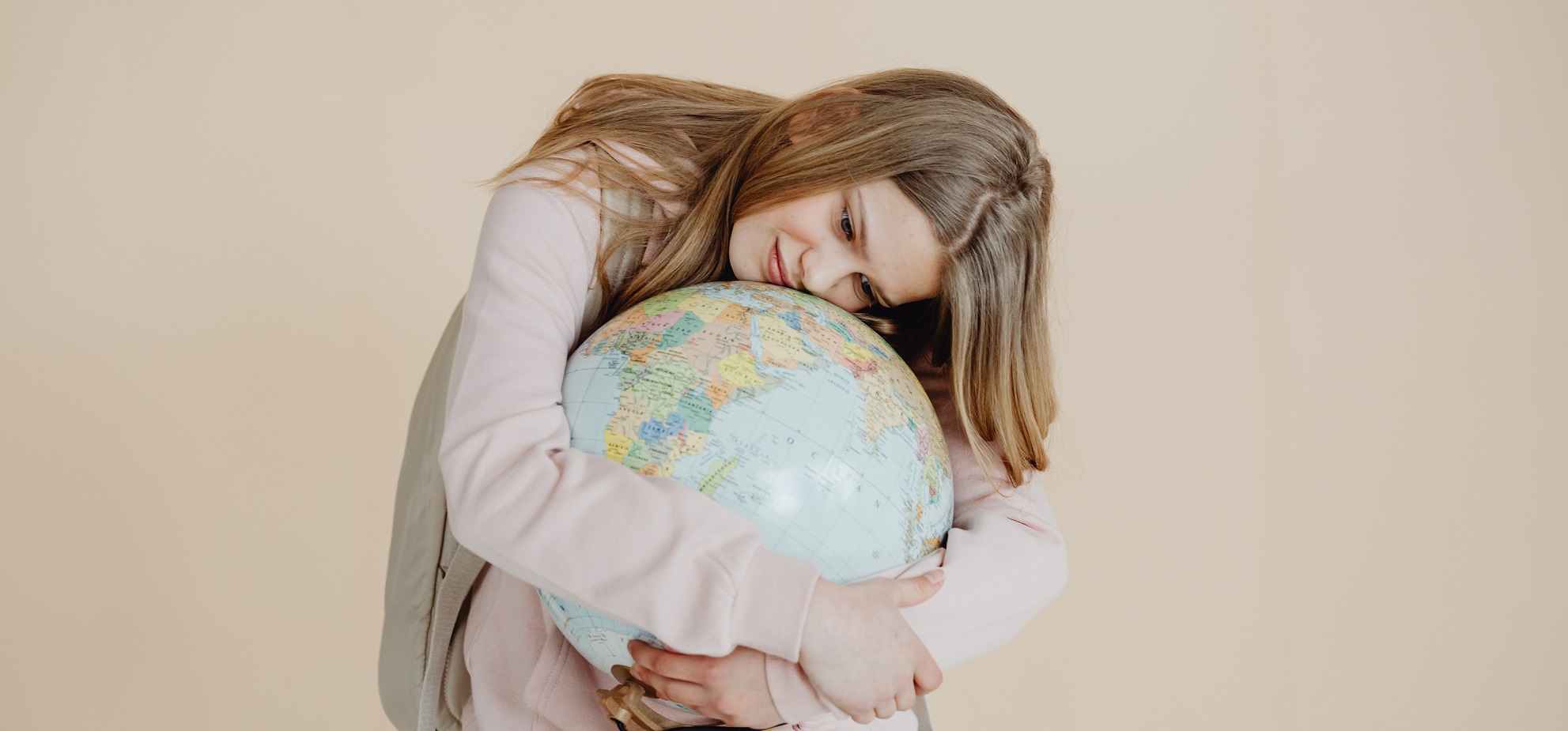 Ein junger Mensch umarmt einen Globus.