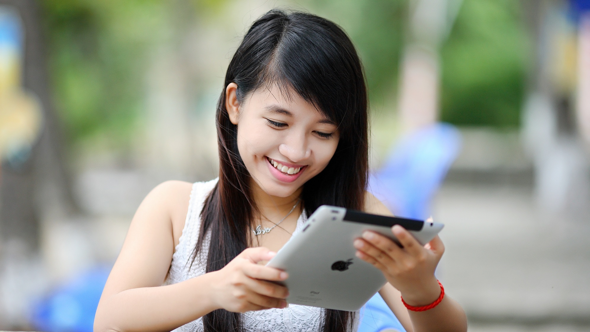Ein Mädchen schaut lächelnd auf ein Tablet.