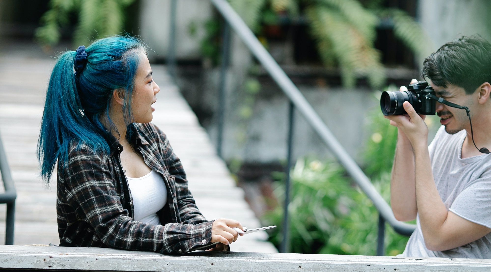 Ein junger Mensch fotografiert ein blauhaariges Mädchen.
