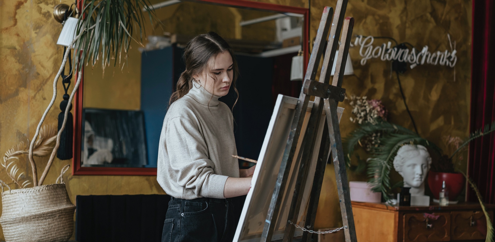Eine junge Frau malt auf einer Staffelei.
