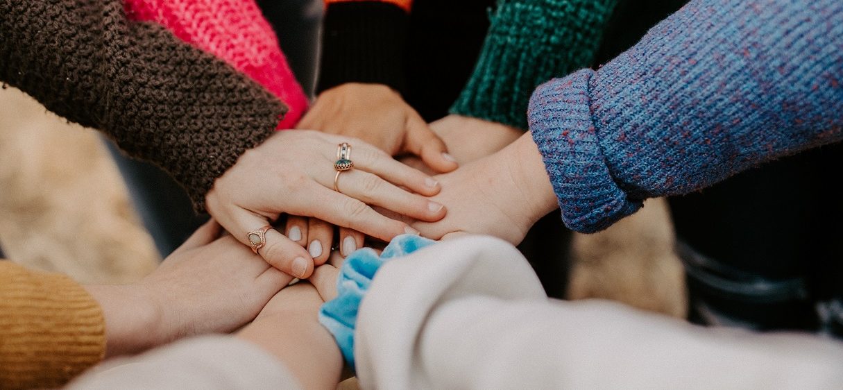 Viele menschen legen in einem Kreis die Hände aufeinander